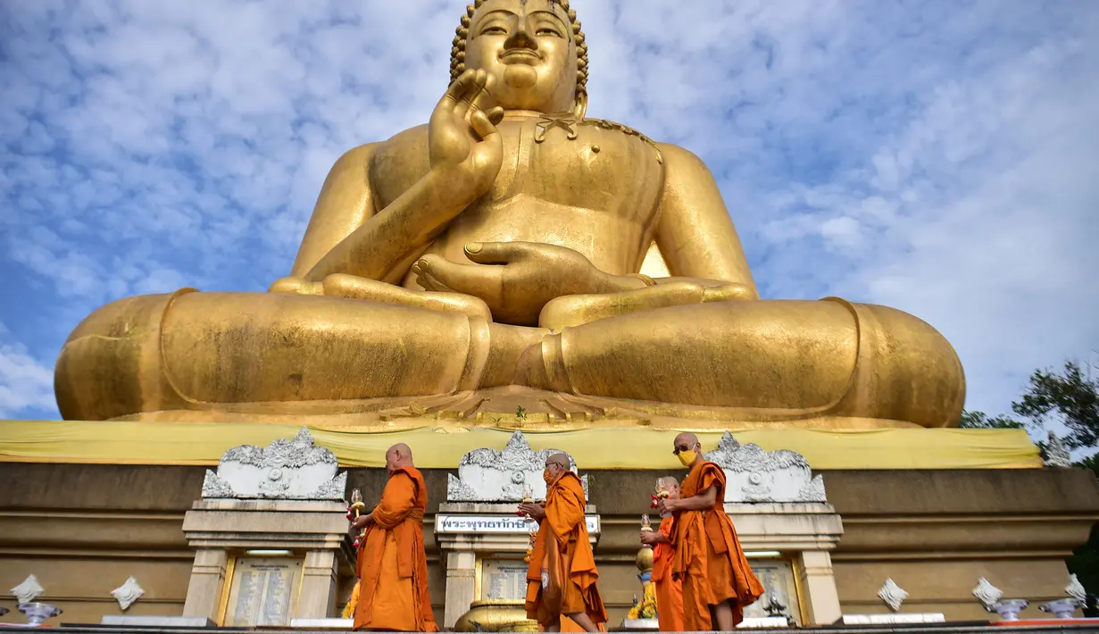 Biksu Buddha berjalan mengelilingi patung Buddha raksasa saat mereka melakukan ritual keagamaan untuk menandai Hari Makha Bucha di kota Narathiwat, Thailand selatan  (6/3/2023). Makha Bucha merupakan salah satu hari raya terpenting bagi para penganut agama Buddha. (AFP/Madaree Tohlala)
