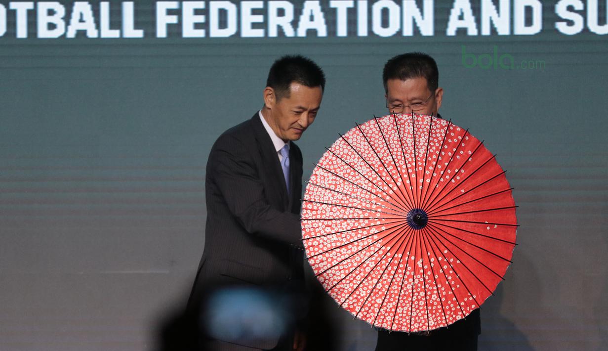 Direktur PT. Suzuki Indomobil Motor, Seiji Itayama memberikan hadiah payung kepada Deputi Presiden AFF, Maj Gen Khiev Sameth di Hotel Mulia, Jakarta, Rabu (2/5/2018). Indonesia berada satu grup dengan Thailand. (Bola.com/Nick Hanoatubun)