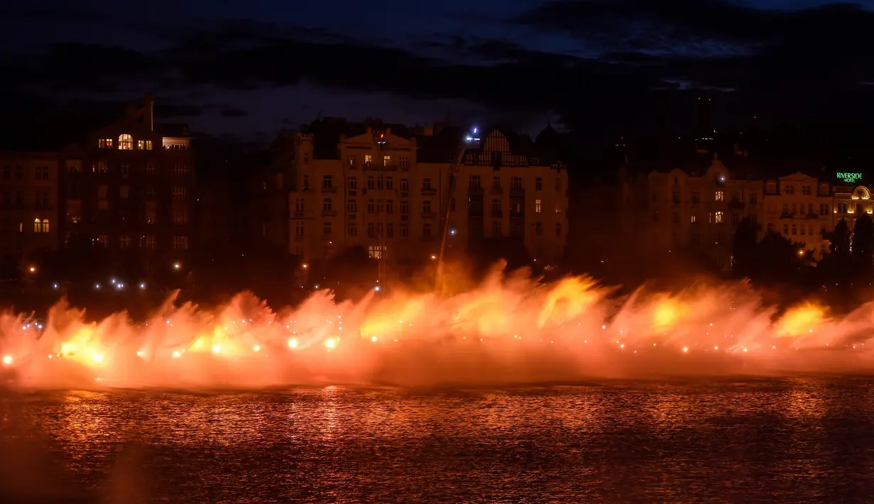 Petugas pemadam kebakaran menyemprotkan air ke Sungai Vltava berhias cahaya kuning untuk menandai HUT ke-100 Ceko di Praha, Sabtu (2/6). (Michal Cizek/AFP)