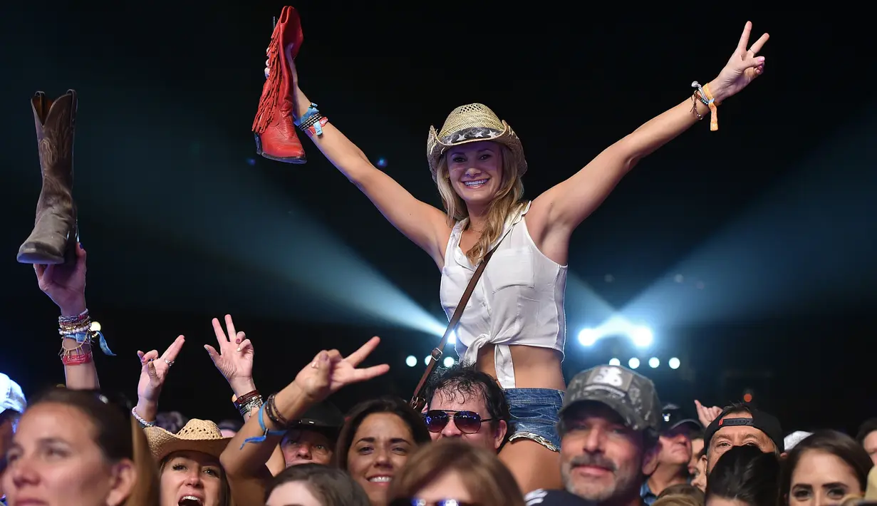 Seorang pengunjung wanita tersenyum saat berjoged menggunakan topi koboi saat menghadiri Festival musik Country Stagecoach di Empire Polo Club di Indio, California, 29 April 2016. (AFP PHOTO/Kevin Winter)