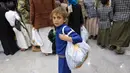Seorang anak laki-laki Yaman membawa tas pakaian barunya di ruang pamer yang membagikan pakaian kepada anak-anak yang kehilangan orang tua dalam konflik, sebagai bagian dari kegiatan amal selama bulan suci Ramadhan, di ibu kota Sanaa (8/4/2022). (AFP/Mohammed Huwais)