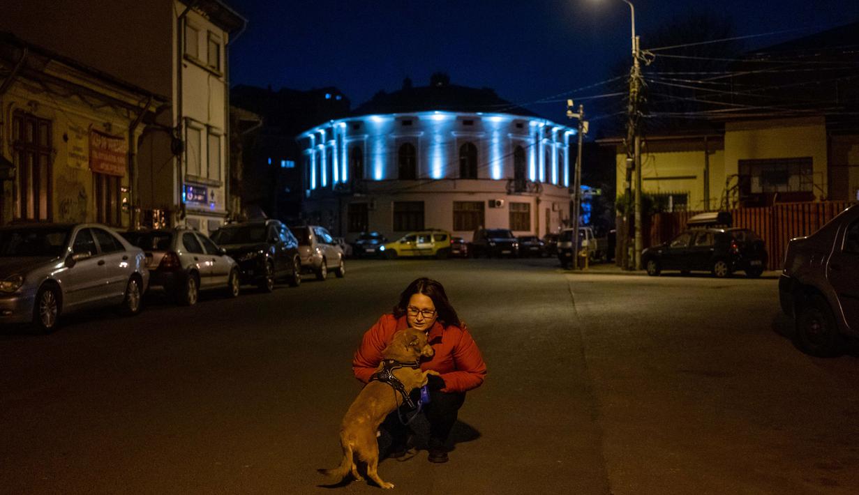 Agnes Nicolaesu (43) berpose dengan anjingnya Boby (13) di Bucharest (27/3/2020). Undang-undang militer, yang disahkan pemerintah Rumania untuk mengurangi penyebaran virus corona, menyatakan berjalan bersama anjing adalah salah satu  kegiatan yang masih diizinkan. (AFP/Andrei Pungovschi)