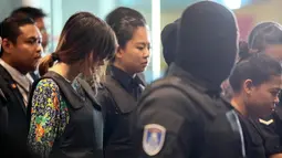 Tersangka kasus pembunuhan Kim Jong-nam, Siti Aisyah dan Doan Thi Huong, dikawal polisi menuju Bandara Internasional Kuala Lumpur, Selasa (24/10). Keduanya melakukan reka ulang kejadian di tempat keduanya dituding meracuni Kim Jong-nam. (AP/Sadiq Asyraf)