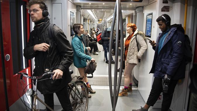 Dua wanita tanpa mengenakan celana berada di dalam kereta selama No Pants Subway Ride ke-18 di Amsterdam, Belanda (13/1). Acara ini dimulai pada tahun 2002 dengan peserta hanya tujuh orang. (AFP Photo/Olaf Kraak)