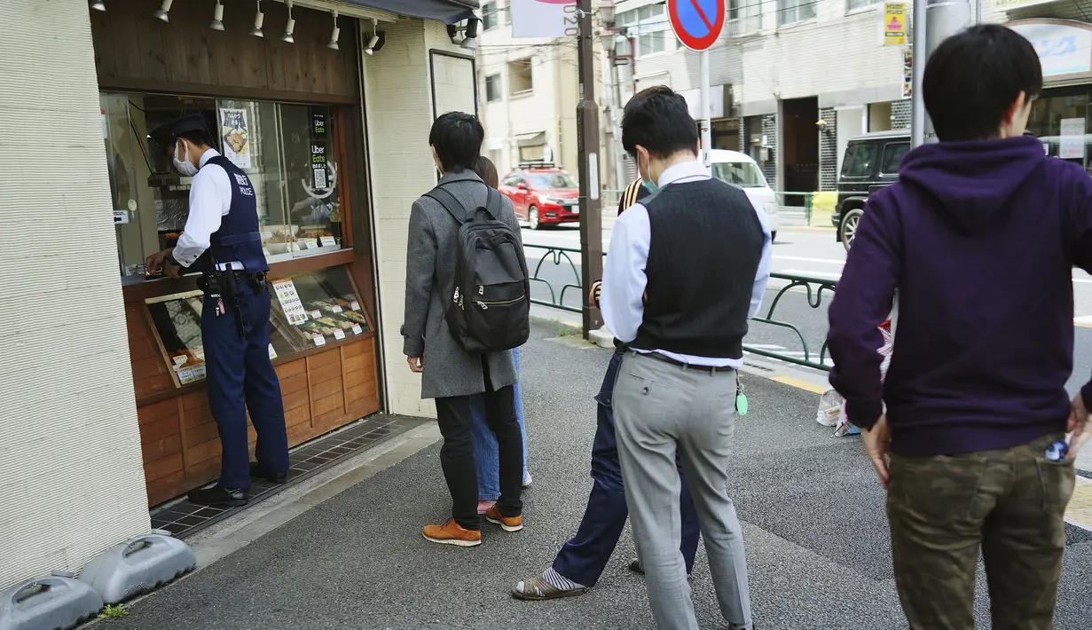 Sejumlah orang mengantre untuk membeli makan siang di sebuah toko di Tokyo, Jepang, 22 April 2020. Pemerintah Jepang dinilai memberikan pesan yang tidak konsisten dan tidak memberikan insentif untuk tetap tinggal di rumah selama pandemi COVID-19 ini. (AP Photo/Eugene Hoshiko, File)