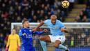 Bek Manchester City, Vincent Kompany, berebut bola dengan striker Leicester City, Jamie Vardy, pada laga Premier League di Stadion King Power, Sabtu (18/11/2017). Manchester City menang 2-0 atas Leicester City. (AFP/Lindsey Parnaby)