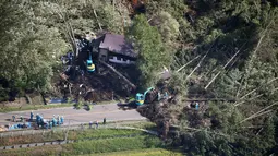 Petugas mencari korban yang selamat dari sebuah bangunan yang roboh akibat tanah longsor yang disebabkan oleh gempa di Kota Atsuma, Hokkaido, Jepang, Kamis (6/9). Akibat tanah longsor tersebut dua orang tewas dan puluhan hilang. (Kyodo News via AP)