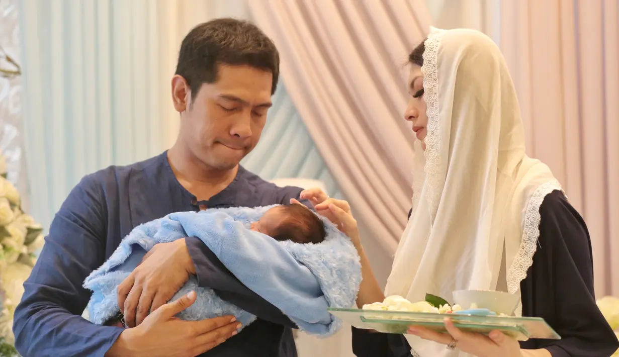 Parvaiz Farezell Shaqul Nugroho anak kedua pasangan ini terlelap dalam gendongan Adi. Sedangkan donita disebelahnya membawa peralatan untuk potong rambut. Seperti gunting, air, bedak dan lainnya. (Adrian Putra/Bintang.com)