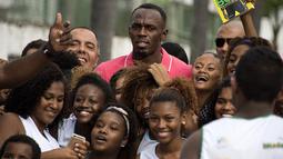 3.	Sprinter Jamaika juara Olimpiade,Usain Bolt, berfoto dengan anak-anak saat mengunjungi kompleks olah raga Mangueira, Rio de Janeiro, Brasil. Jumat (16/4)