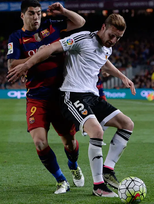 Bek Valencia, Shkodran Mustafi (depan) mengontrol bola dari kawalan penyerang Barcelona, Luis Suarez di pertandingan liga Spanyol di Camp Nou stadium, Spanyol (18/4). Valencia menang atas Barcelona dengan skor 2-1. (AFP PHOTO/ JOSEP LAGO)