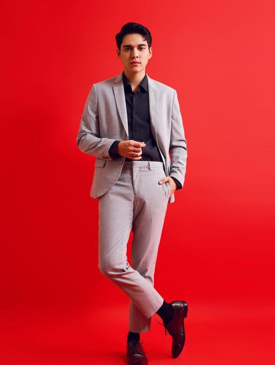 Pesona Maxime Bouttier tak perlu disangsikan lagi. Salah satu foto menampilkannya mengenakan kemeja hitam lengan panjang berbalut setelan jas abu-abu. Kaus kaki hitam dan sepatu pantofel hitam bertali menyempurnakan penampilannya. Auranya makin memancar berkat latar merah polos. Terasa kontras sekaligus menajamkan derajat ketampanan. (Foto: Dok. Instagram @bouttier_maxime)