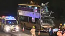 Petugas pemadam kebakaran, petugas medis, dan polisi berkumpul dekat bus tingkat dua yang menabrak pohon di Kwu Tung, Hong Kong, Rabu (18/12/2019). Kecelakaan tersebut mengakibatkan enam orang tewas dan belasan lainnya luka-luka. (Philip FONG/AFP)