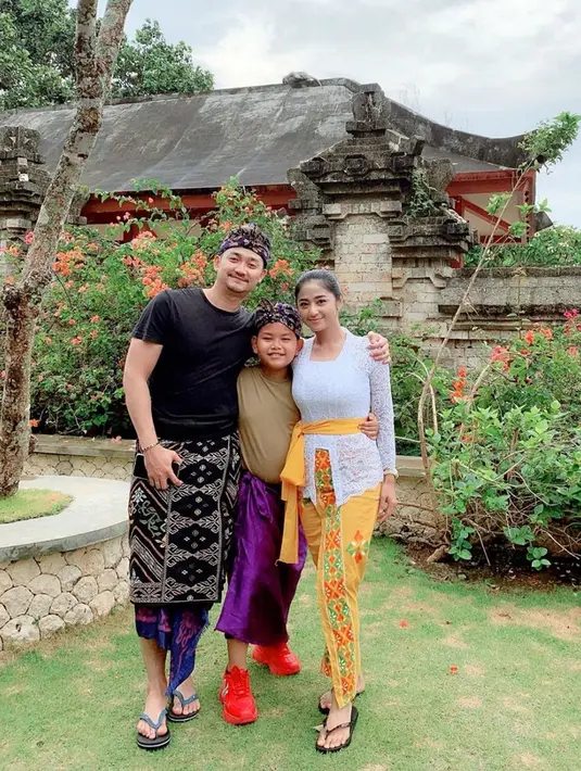Liburannya kali ini ia mengajak suami dan anaknya. Tak lupa ia pun juga berpenampilan layaknya masyarakat Bali. DP mengenakan kebaya putih, lalu suami dan anaknya mengenakan udeng. (Liputan6.com/IG/@dewiperssikreal)