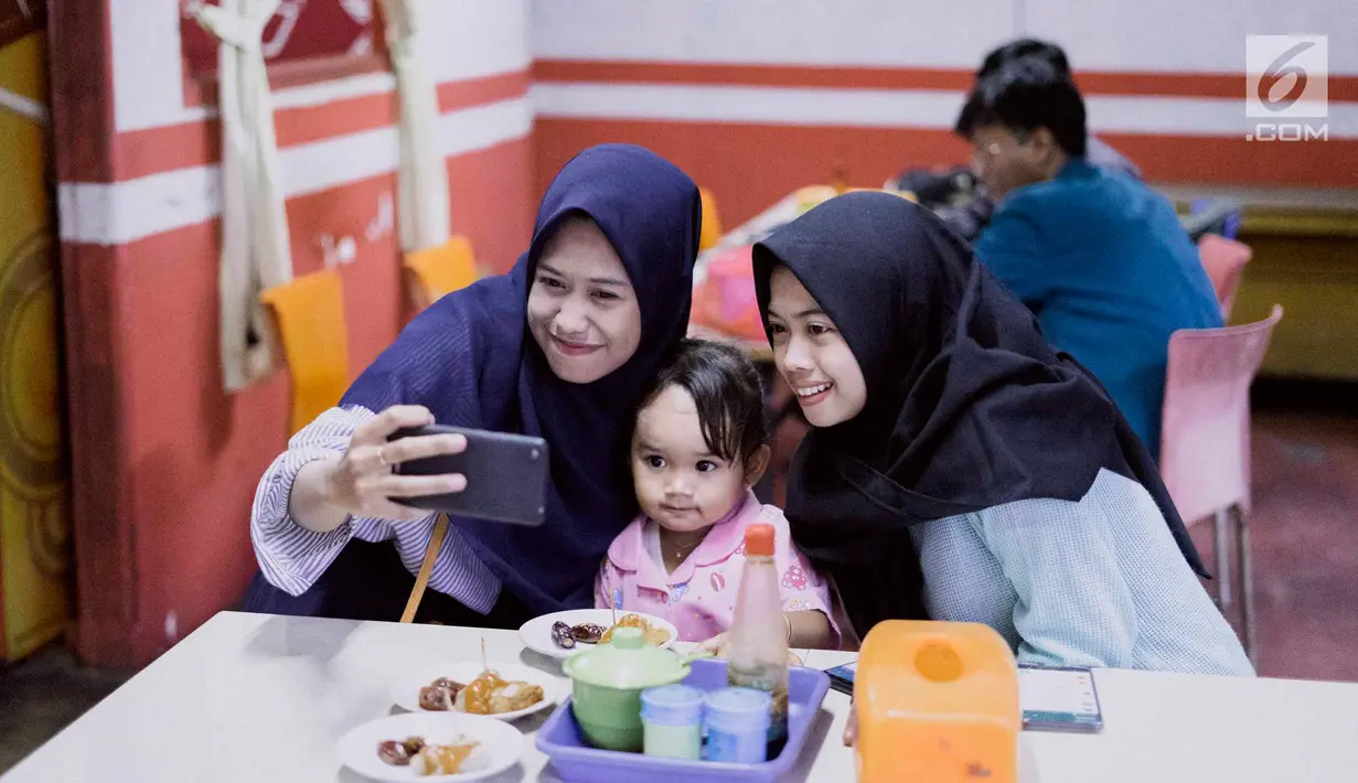 Pengunjung berselfie di Kedai Soto Kauman Express Sawangan, Depok, Jawa Barat, Senin (13/5). Selama Ramadan, kedai soto ini menyediakan satu paket menu buka puasa yang terdiri dari soto, siomay, kurma, dan minuman yang cukup dibayar dengan doa pada secarik kertas. (Liputan6.com/Immanuel Antonius)