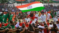 Seorang gadis mengibarkan bendera India saat para siswa melakukan tarian selama perayaan Hari Kemerdekaan India, di Jammu, India, (15/8). India merdeka dari kolonialis Inggris pada tahun 1947. (AP Photo / Channi Anand)