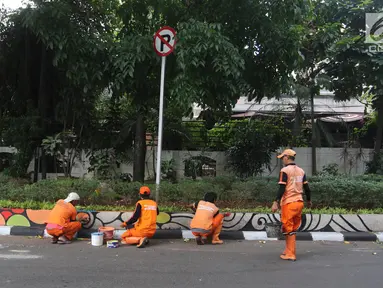 Petugas PPSU Gondangdia mengecat pembatas jalan dengan warna-warni Asian Games di kawasan Menteng, Jakarta, Kamis (12/7). Cat lukisan dinding beraneka gambar dan bentuk untuk menyambut HUT kemerdekaan RI dan Asian Games 2018. (Liputan6.com/Arya Manggala)