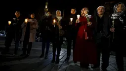 Warga Suriah yang tinggal di Turki memegang lilin dan bunga di lokasi bom bunuh diri di Sultanahmet Square, Istanbul, Rabu (13/1). Bunga dan lilin tersebut wujud belasungkawa untuk korban ledakan di Turki. (REUTERS/Osman Orsal)