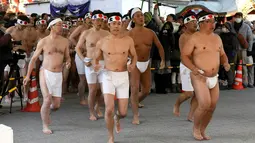 Penganut agama Shinto bersiap menyucikan tubuh dan jiwa mereka dengan mandi air dingin di Kuil Kanda, Tokyo, Jepang (13/1). Mandi air dingin ini merupakan ritual yang digelar untuk menyucikan tubuh dan jiwa mereka. (AFP Photo/Toshifumi Kitamura)