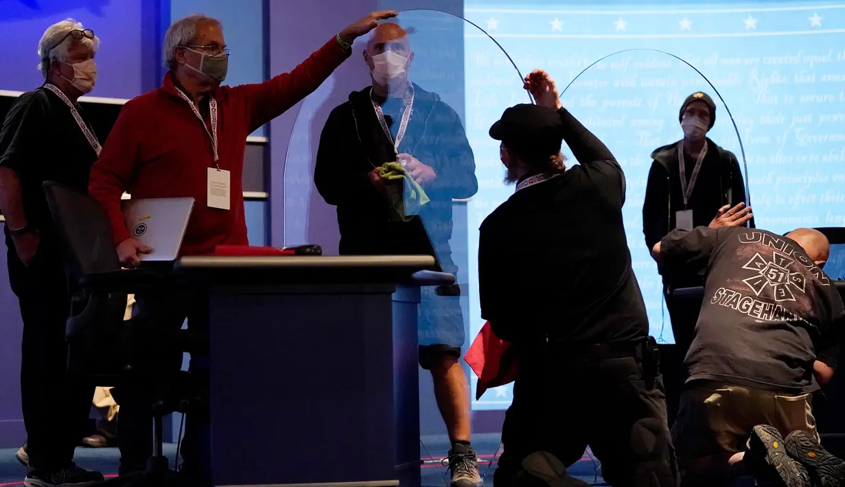 Tim produksi memeriksa kaca plexiglass di atas panggung yang akan berfungsi sebagai penghalang untuk mengurangi resiko penyebaran COVID-19 saat persiapan untuk debat calon wakil presiden AS di Universitas Utah, Salt Lake City, Selasa (6/10/2020). (AP Photo/Julio Cortez)