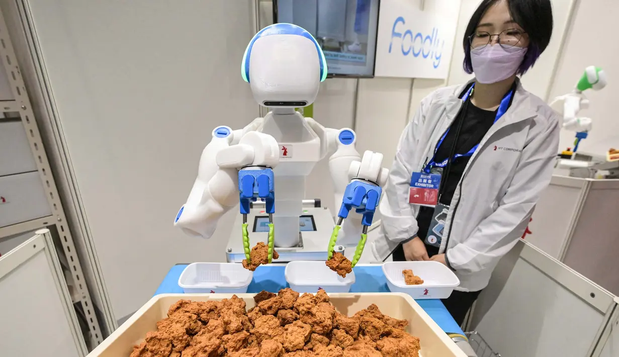 Sebuah robot menyortir dan menempatkan potongan ayam goreng ke dalam wadah. (Richard A. Brooks/AFP)