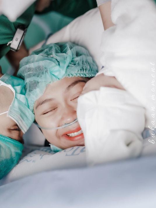 Ria Ricis begitu bahagia usai menjalani operasi caesar. Terlihat ia tersenyum saat diberi kecupan oleh suami dan bayinya. (Foto: Instagram/@riaricis 1795)
