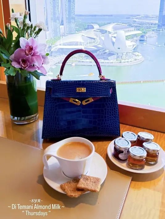 Selama hamil, Syahrini berada di Singapura. Ia pun memamerkan tas Hermes saat minum almond milk. Tas Hermes tersebut model K25 sellier (HSS) special order bleu electric & bleu marine shiny alligator with gold hardware Rp 1.192.000.000. [@princessyahrini]