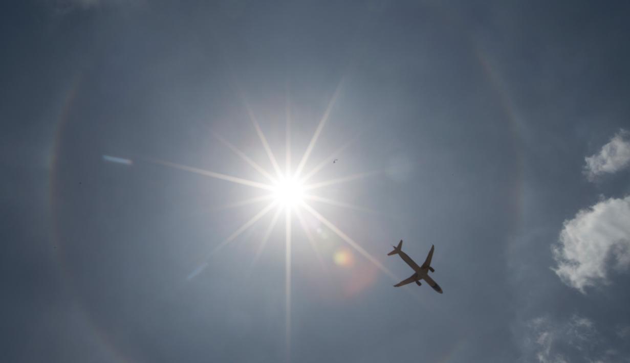 Pesawat komersil melintas dilatari fenomena halo matahari di Meksiko, Sabtu (7/7). Fenomena halo matahari terjadi karena pembiasan kristal es yang berada di sekitar matahari sehingga membentuk cincin pelangi yang mengelilingi matahari (AP/Moises Castillo)