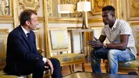 Presiden Prancis Emmanuel Macron (kiri) berbincang dengan Mamoudou Gassama di Istana Elysee, Paris, Prancis, Senin (29/5). Imigran asal Mali tersebut memperoleh penghargaan setelah menyelamatkan seorang balita di Paris. (AP Photo/Thibault Camus, Pool)