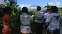 Warga memantau aktifitas Gunung Agung di Pos Pemantauan Desa Rendang, Karangasem, Bali, Jumat (29/9). Petugas gabungan akan menyisir kawasan rawan bencana untuk mengevakuasi warga yang belum mengungsi. (Liputan6.com/Gempur M Surya)