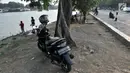 Sepeda motor terparkir di bawah pohon di Danau Sunter, Jakarta, Senin (22/7/2019). Tidak adanya fasilitas parkir di kawasan tersebut menyebabkan pengunjung Danau Sunter memarkirkan sepeda motor mereka di sepanjang trotoar sehingga mengganggu akses pejalan kaki. (merdeka.com/Iqbal Nugroho)