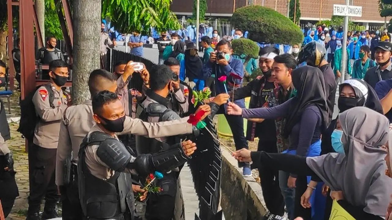 Mahasiswa membagikan bunga kepada Brimob Polda Riau di sela-sela demo tolak Omnibus Law.