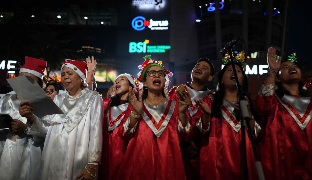 Bertempat di jalur pedestrian di depan FX Sudirman, Jakarta, acara ini melibatkan sekitar 1.200 hingga 1.400 penyanyi dari berbagai gereja dan komunitas. Tampak dalam foto, Umat Kristiani menyanyikan lagu-lagu Natal di Jakarta, Selasa 23 Desember 2025. (AP Photo/Dita Alangkara)