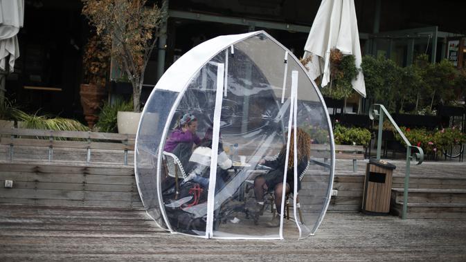 Sejumlah orang menyantap makanan di sebuah dining bubble, instalasi tempat makan berbentuk gelembung, di luar ruangan ketika pandemi COVID-19 masih terus merebak di Yerusalem pada 26 November 2020. Dining bubble pun hadir sebagai sebuah solusi pragmatis untuk tantangan tersebut (Xinhua/Muammar Awad)