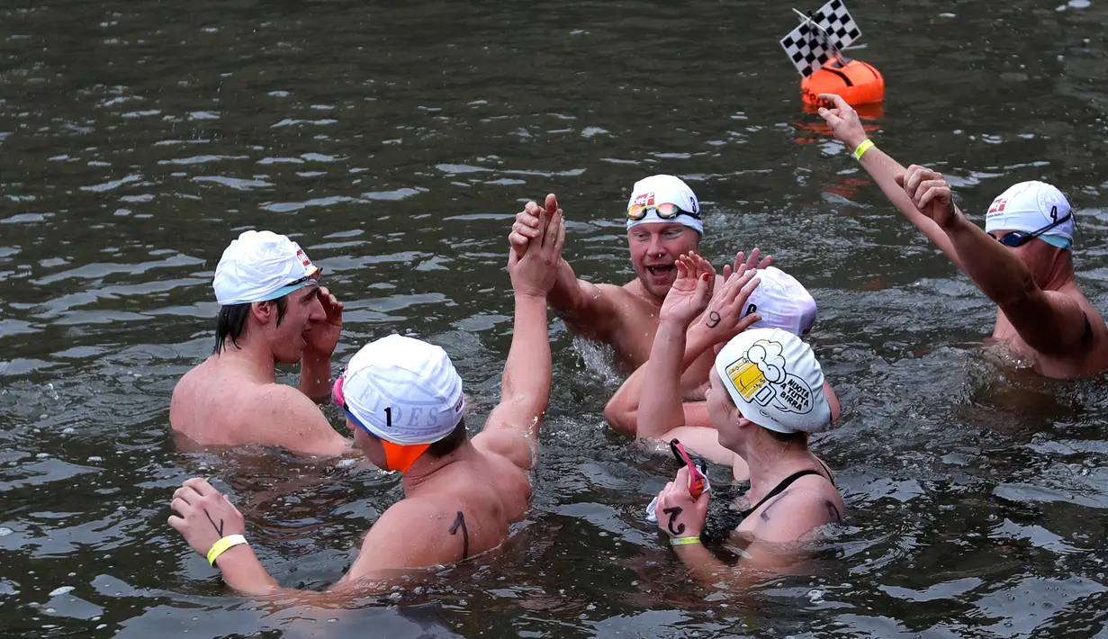 Peserta merayakan setelah melewati garis finis dalam kompetisi berenang Natal tahunan di sungai Vltava, ibu kota Republik ceko, Praha, Rabu (26/12). Dalam menyemarakkan Natal, peserta mengikuti lomba renang di sungai bersuhu dingin. (AP/Petr David Josek)