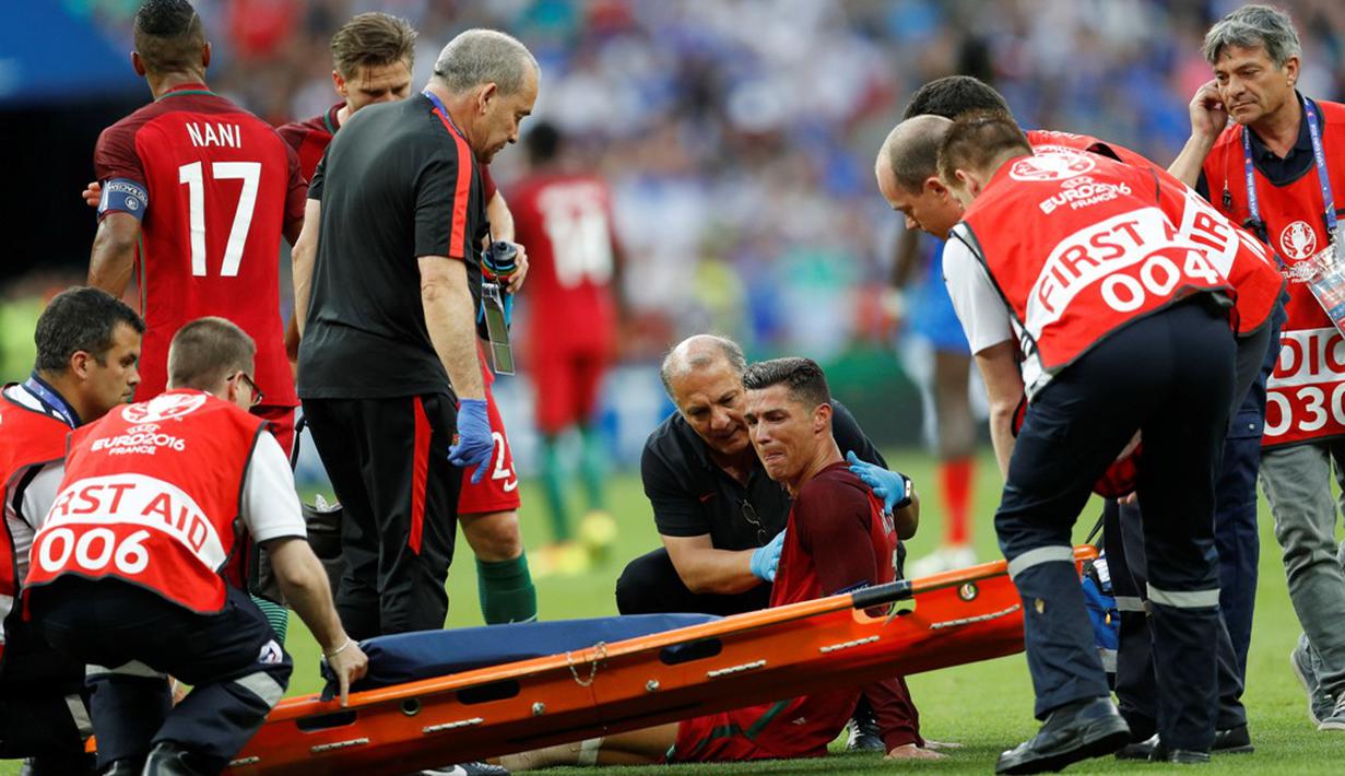 Striker Portugal, Cristiano Ronaldo, menangis sebelum ditandu karena cedera setelah dilanggar pemain Prancis, Dimitri Payet, pada laga final Piala Eropa 2016 di Stade de France, Saint-Denis, Senin (11/7/2016) dini hari WIB. (Reuters/Darren Staples)