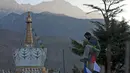 Seorang pria berada di atas tiang untuk memasang bendera warna-warni pada hari ketiga Tahun Baru Tibet di Dharmsala, India (18/2). Umat Buddha Tibet percaya, bendera warna-warni berisi doa itu akan menyebarkan doa ke dunia. (AP/Ashwini Bhatia)