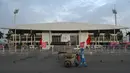 <p>Seorang pekerja mendorong troli di depan Stadion Nasional My Dinh, tempat utama Pesta Olahraga Asia Tenggara (Southeast Asian Games) atau biasa disingkat SEA Games ke-31, sehari sebelum upacara pembukaan di Hanoi, Vietnam, Rabu (11/5/2022). SEA Games 2021 akan dibuka pada 12 Mei 2022 di Stadion My Dinh dengan mempertandingkan 40 cabang olahraga (cabor) dalam 526 nomor. (TANG CHHIN Sothy / AFP)</p>