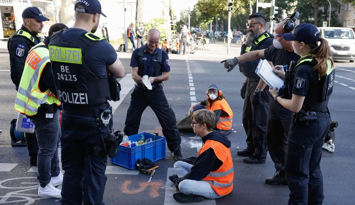Polisi mengepung aktivis iklim dari gerakan Letzte Generation (Generasi Terakhir) yang menempelkan tangan mereka di jalan untuk menarik perhatian pada aksi keadaan darurat iklim, pada tanggal 18 September 2023 di Berlin. (Odd ANDERSEN/AFP)