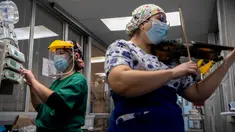 Perawat Chile, Damaris Silva memainkan biola untuk pasien yang terinfeksi COVID-19 di Unit Perawatan Intensif rumah sakit El Pino di Santiago pada 9 Juli 2020. Kegiatan tersebut dilakukan perempuan 26 tahun itu dua kali dalam seminggu setelah shift bekerjanya selesai. (Martin BERNETTI / AFP)