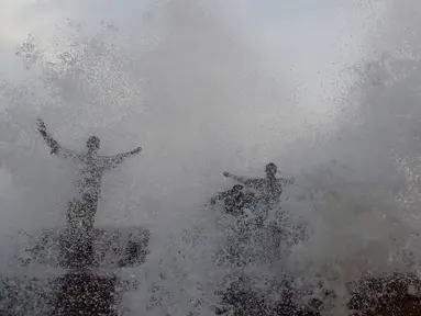 Orang-orang menikmati percikan air ombak selama musim panas di laut Arab di Karachi (14/6/2019). Memasuki musim panas, warga Pakistan ramai-ramai mendinginkan tubuhnya di laut. (AFP Photo/Asif Hassan)