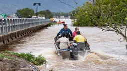 Warga menyeberangi banjir dengan perahu di Cairns pada 18 Desember 2023. (Brian CASSEY/AFP)