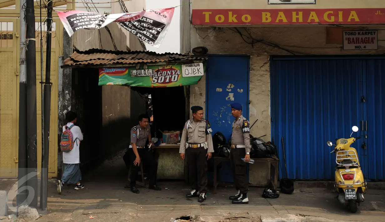 Beberapa petugas kepolisian berjaga di salah satu gang masuk menuju kawasan Kampung Pulo Jakarta, Jumat (21/8/2015). Ribuan aparat gabungan terus berjaga mengawal proses penggusuran warga Kampung Pulo Jakarta Timur. (Liputan6.com/Helmi Fithriansyah)