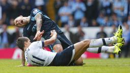 Bek sayap Manchester City, Aleksandar Kolarov terjatuh saat berebut bola dengan gelandang Tottenham, Erik Lamela pada laga Liga Inggris di Stadion White Hart Lane, London, Sabtu (26/9/2015). (Reuters/Eddie Keogh)
