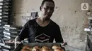 Pekerja membawa loyang roti di dekat papan pesanan para pedagang di sebuah industri rumahan kawasan Tanah Abang, Jakarta, Rabu (11/11/2020). (merdeka.com/Iqbal S. Nugroho)