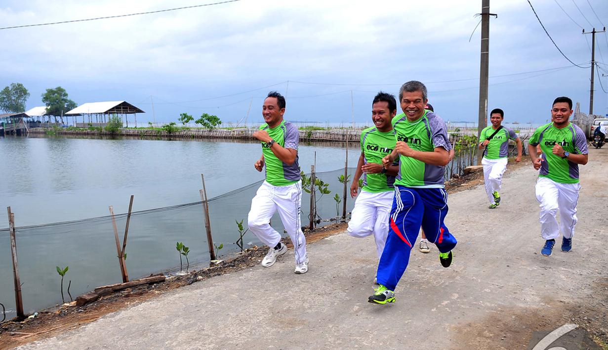 Sejumlah relawan Pertamina Sobat Bumi berlari menuju tempat menanam mangrove di Desa Muara Ujung, Tangerang, Banten, Minggu (7/12/2014). (Liputan6.com/Johan Tallo) 