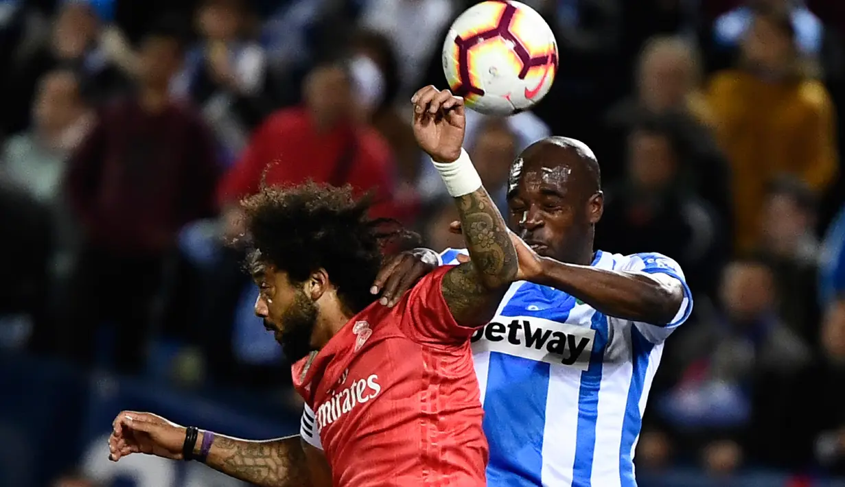 Duel udara bek Real Madrid, Marcelo (kiri) dan pemain Leganes, Allan Nyom dalam lanjutan La Liga 2018-2019 di Estadio Municipal Butarque, Senin (15/4). Real Madrid hanya mampu meraih hasil imbang 1-1 saat bertandang ke markas Leganes. (PIERRE-PHILIPPE MARCOU / AFP)