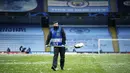 Petugas membuang salju yang menutupi rumput lapangan jelang laga Manchester City melawan PSG pada laga semifinal Liga Champions di Stadion Etihad, Rabu (5/5/2021). (AP/Dave Thompson)