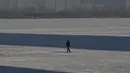 Seorang pria berjalan di sungai beku di Harbin, di provinsi Heilongjiang timur laut China, pada 4 Januari 2023, menjelang Festival Es dan Salju Internasional Harbin China ke-39. (AFP/Hector Retamal)