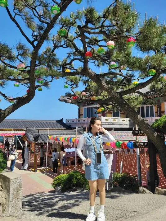 Kombinasi overall denim, inner putih, dan sneakers warna putih senada  bikin Ayu Ting Ting terlihat bersinar di bawah terik matahari.  [Foto: IG/ayutingting92].