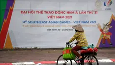Seorang perempuan mengendarai sepedanya melewati tanda untuk Pesta Olahraga Asia Tenggara (Southeast Asian Games) atau biasa disingkat SEA Games ke-31, sehari sebelum upacara pembukaan di Hanoi, Vietnam, Rabu (11/5/2022). SEA Games 2021 akan dibuka pada 12 Mei 2022 di Stadion My Dinh dengan mempertandingkan 40 cabang olahraga (cabor) dalam 526 nomor. (TANG CHHIN Sothy / AFP)